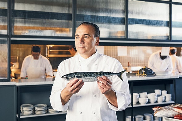 Chef standing in front of a peek-a-boo kitchen restaurant designs