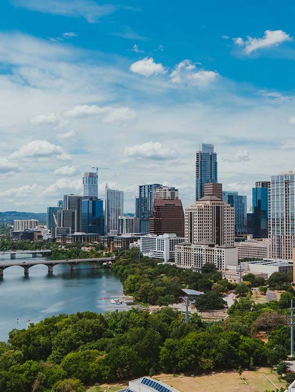 An aerial view of the Austin skyline. The Colorado river is in view as well as many large skyscrapers