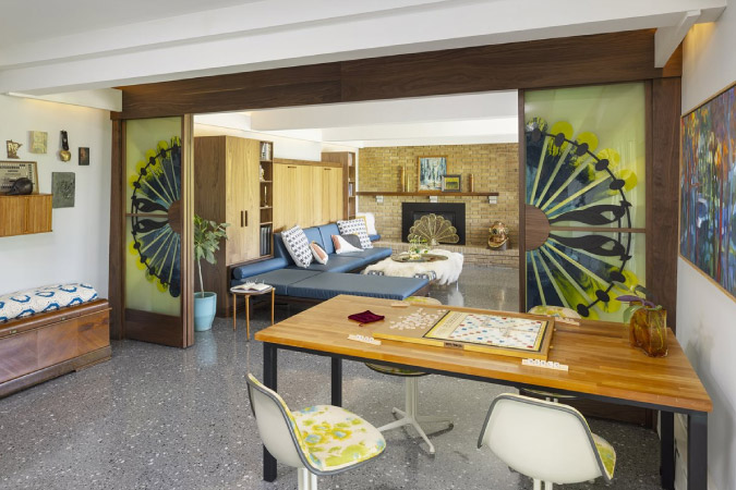 A basement featuring gray terrazzo floors, an ornate room divider, mid-century modern furniture, and other home remodeling ideas that create flex zones in your basement.