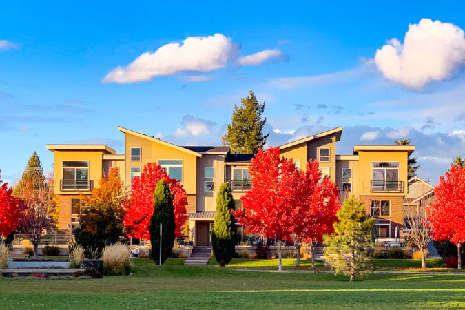 A row of modern townhouses in Kendall Yards — one of the best Spokane Neighborhoods — featuring vibrant fall foliage and an expansive green lawn.