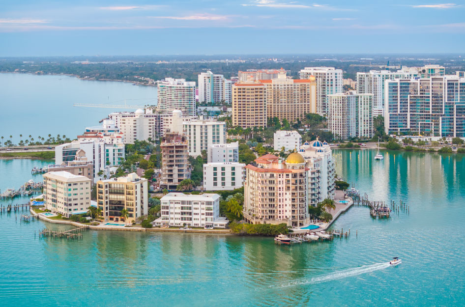Aerial view of coastal condo buildings and the surrounding Gulf waters in Sarasota, Florida.