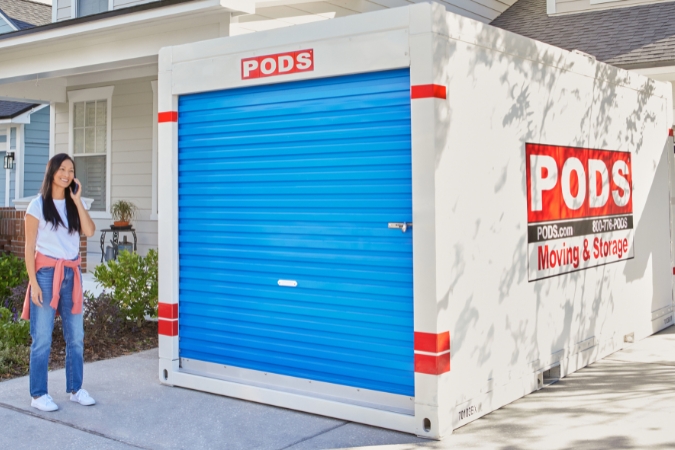A woman, who is now living in Melbourne, FL, stands beside the PODS portable moving container that was delivered to the driveway of her new home.