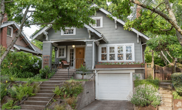 A two-story bungalow in Portland’s Hollywood neighborhood is built on a hill and features a long set of steps leading up to the door and a single-car garage on the lower level.