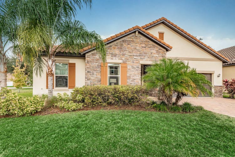 Beautiful residential home in Carrollwood, Florida, featuring a stone facade, clay tile roof, and lush landscaping.