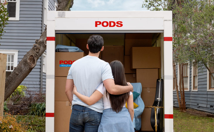 A couple looking at their loaded PODS container as they stand with their arms around each other