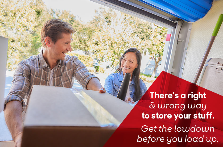 A mature couple smiles while placing boxes and furniture inside a portable storage container