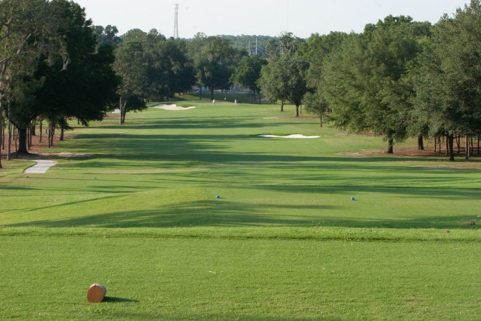 A tree-lined golf course fairway at the Ocala Golf Club highlights one of the pros in the pros and cons of living in Ocala, FL.