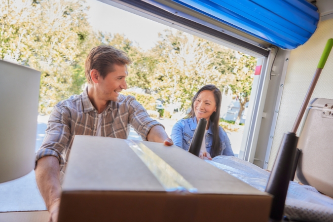 View from inside a PODS portable moving container of a man and woman smiling at each other as they load in boxes during a military move.