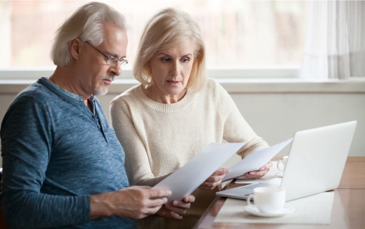 An older couple sits down together at a laptop computer to review renters and homeowners insurance. 
