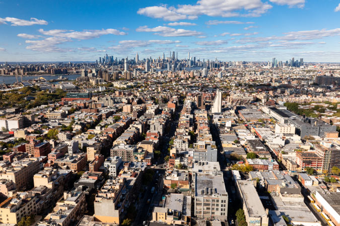 Aerial view of Brooklyn with Manhattan visible in the distance, showcasing 2 of the 5 boroughs of New York.