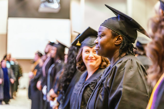 Graduates of Chattahoochee Technical College stand together dressed in cap and gown during a graduation ceremony.