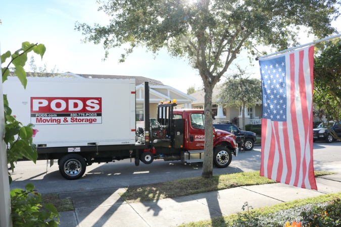 A PODS truck delivering a portable storage container outside a suburban home as part of a military move with flexible storage options.