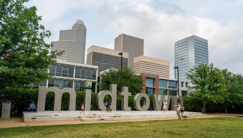 A few locals explore a giant “midtown” sculpture in a park in Midtown Houston.
