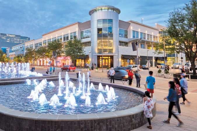 Locals stroll past a large water fountain outside the Legacy West shopping center in Plano — one of the best cities near Dallas, TX.