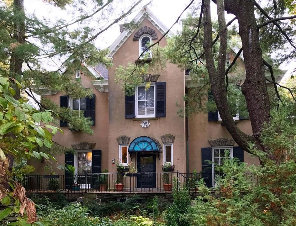 A large, upscale home in Chestnut Hill, one of the best Philadelphia neighborhoods. The home features a stucco exterior and decorative elements above the door and windows.