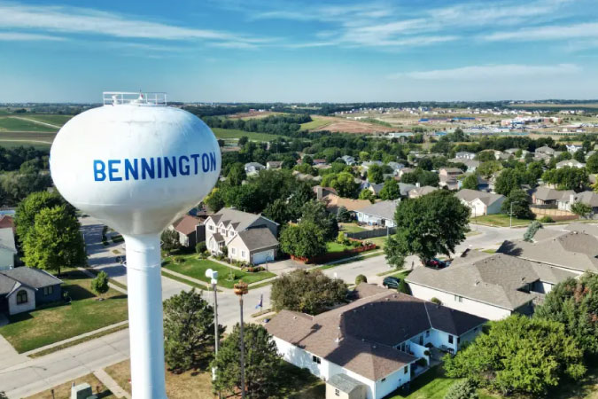 Aerial view of a residential neighborhood and water tower in Bennington — one of the best Omaha suburbs — on a sunny day.