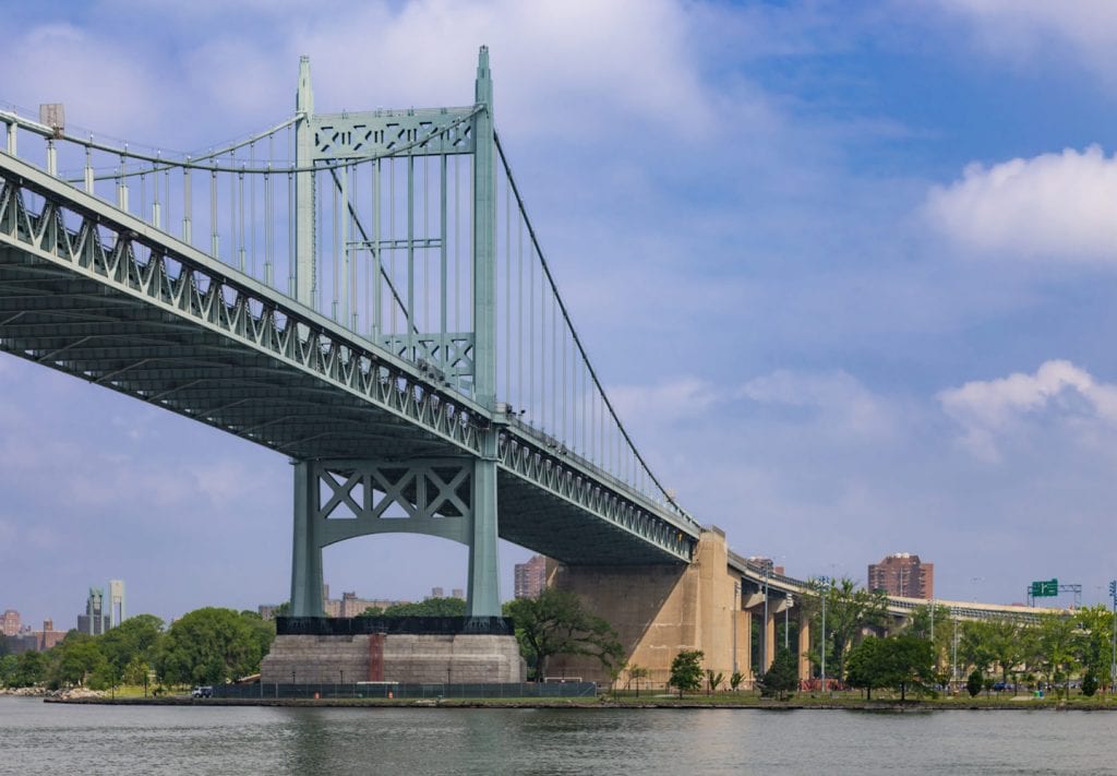 A train crossing a bridge over a body of water
Description automatically generated