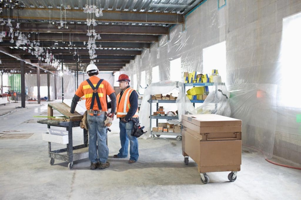 Construction workers talking inside a facility that's being remodeled