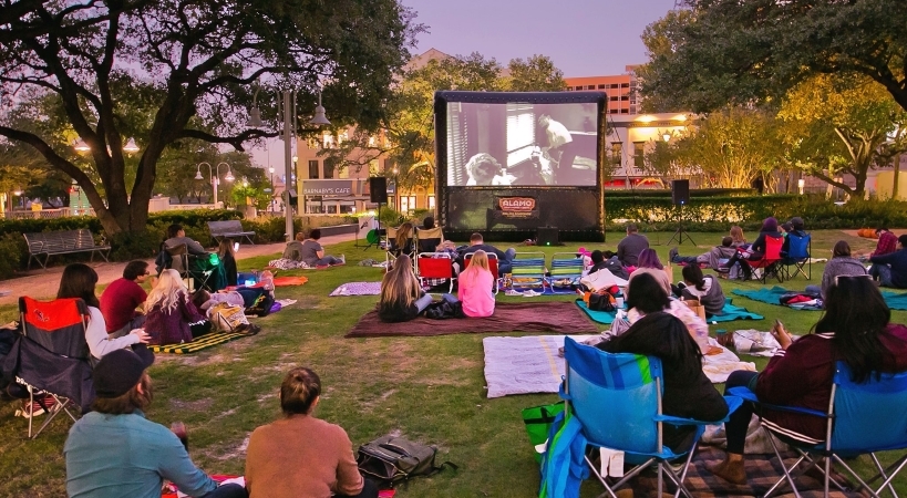Houston locals are sitting on lawn chairs and blankets, watching a free movie in a park in Downtown, one of the best neighborhoods in Houston.
