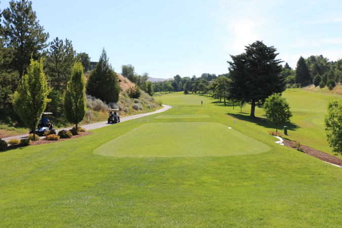 Wide-angle view of the green fairways and manicured greens at Crane Creek Country Club, nestled against the scenic rolling foothills of the Treasure Valley.