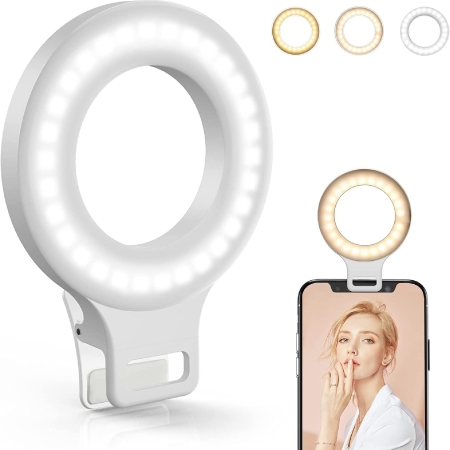 A mini ring light with three light settings (warm, neutral, and cool) with an inset image of it attached to the top of a smartphone with a woman’s photo on the screen.