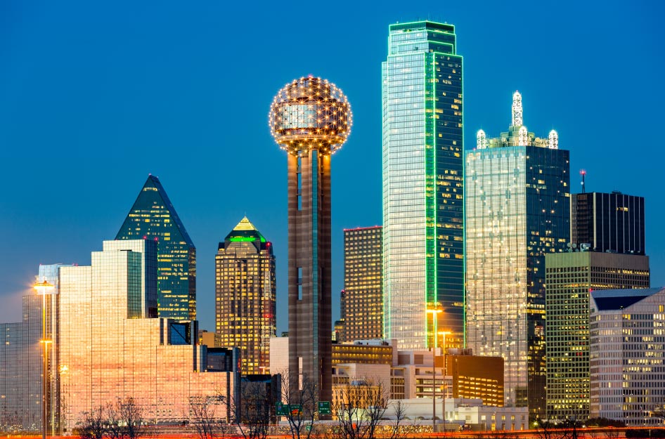 Dallas city skyline just before sunset, with the buildings lit up for the evening