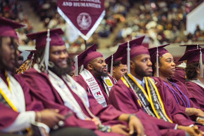 University students sit in cap and gown at an NCCU graduation ceremony in Durham, NC.