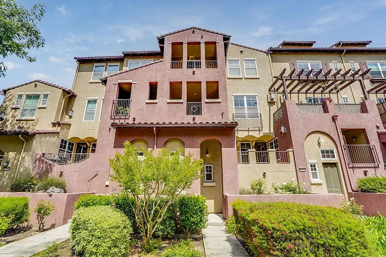  A row of pink and tan condos in the North Valley neighborhood in San Jose, California. The parking lot is slick from a recent rain storm.  