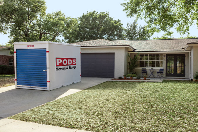 A PODS portable storage container is sitting in the driveway of a residential home, ready to be used as on-site storage during home renovation.