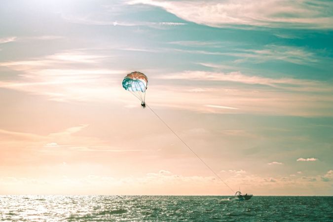 People living in Clearwater, FL, are parasailing above the Gulf waters off Clearwater Beach during sunset.