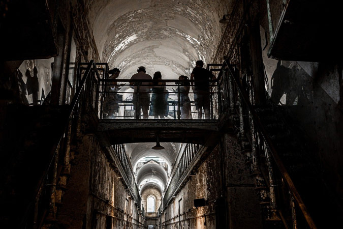 Visitors stand on an elevated walkway during a tour of the Eastern State Penitentiary.