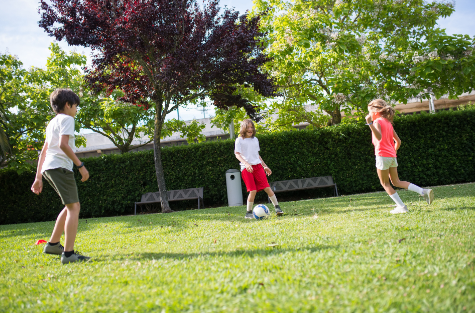 Three young kids play soccer in the grass in a family friendly neighborhood in Chicago.