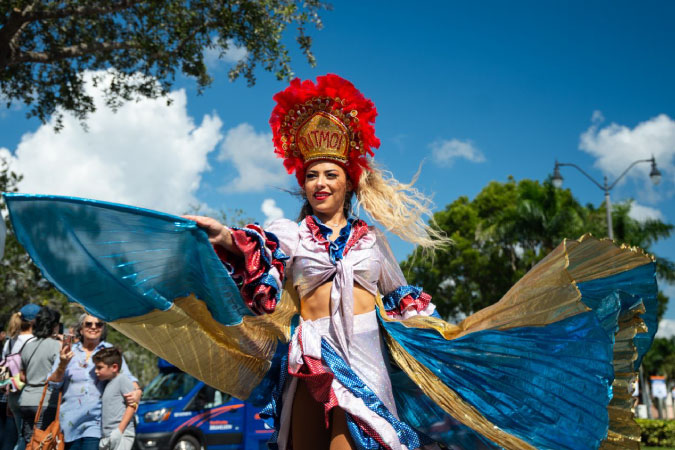 A dancer in colorful traditional costume performs during a Miami street festival parade — a good example of the cultural diversity you find while living in Florida.
