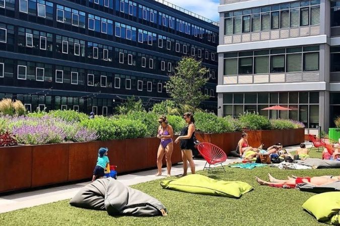 Two women and a small child are enjoying a sunny day on a rooftop patio while living in Staten Island.