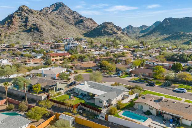 an expansive neighborhood in Camelback East in Phoenix, AZ. There are mountains in the background and a few green trees in the foreground. 