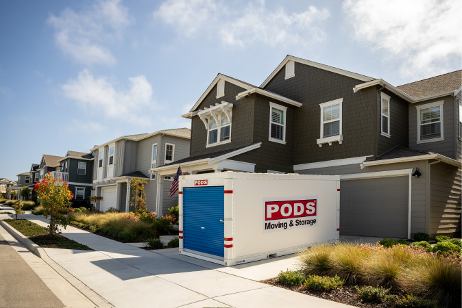 Exterior view of a large, new construction home with a PODS portable container positioned in the driveway
