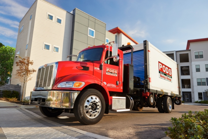 A PODS truck transporting a PODS portable storage container filled with summer storage for college students from an apartment complex.