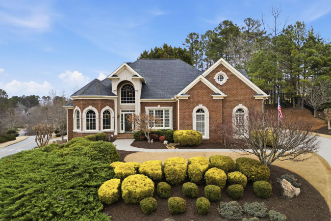 A beautiful two-story brick home in Canton, GA, with arched windows, impressive entryway, and a neatly manicured lawn.