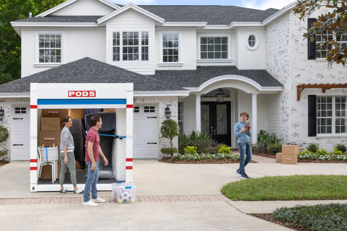 A teenager is holding a football as his parents prepare to unload their PODS portable moving container — one of the final steps of their moving day checklist.