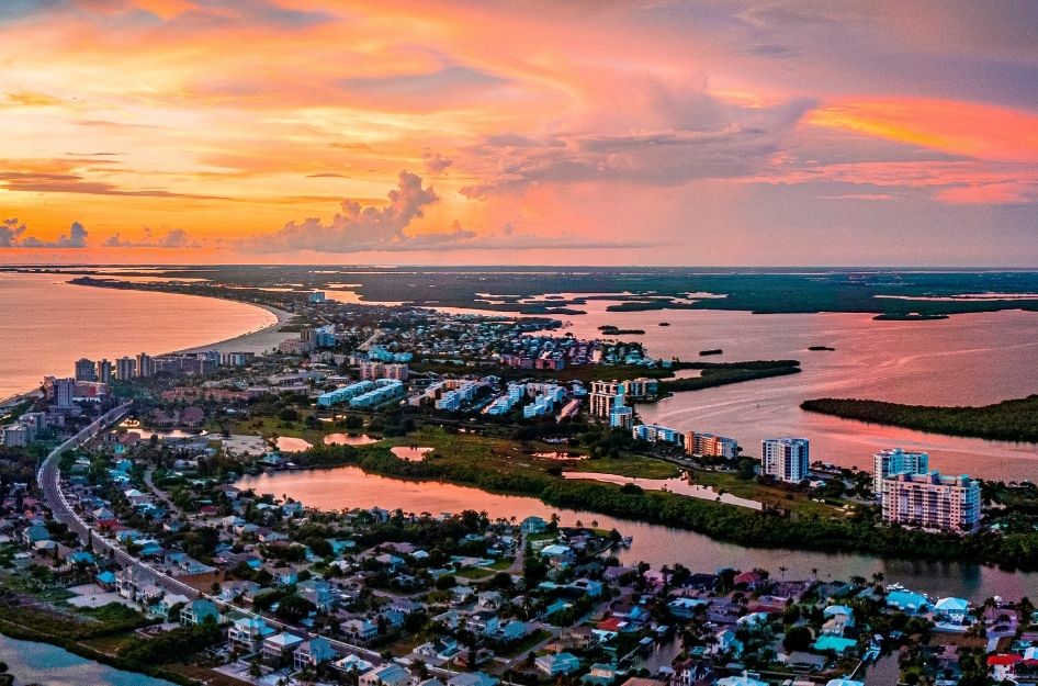 Aerial view of Fort Myers Beach at sunset, with coastal neighborhoods and shimmering gulf waters — just two of the things that make living in Fort Myers, Florida, so enjoyable.