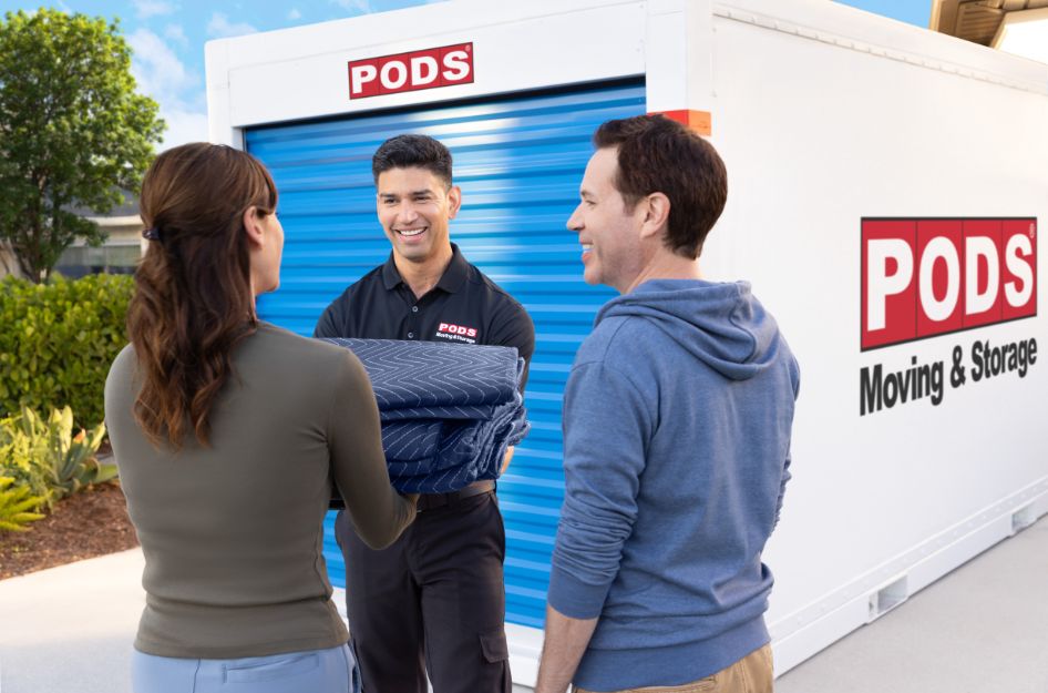 A couple speaks with a PODS employee in front of a portable storage container while comparing PODS vs U-Box for their move.