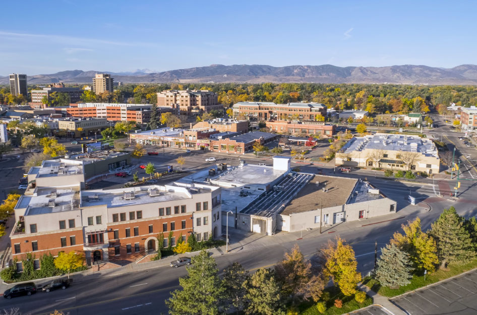 Aerial view of Downtown Fort Collins and a mountain range in the distance.
