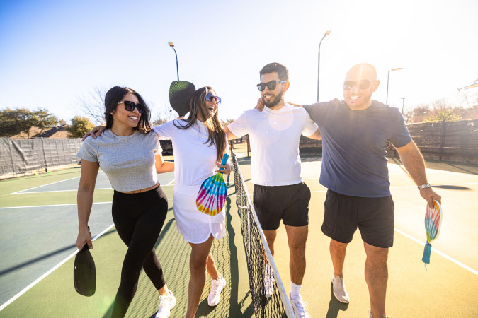 Friends walk arm in arm off the pickleball court after playing a game in Princeton, Texas.