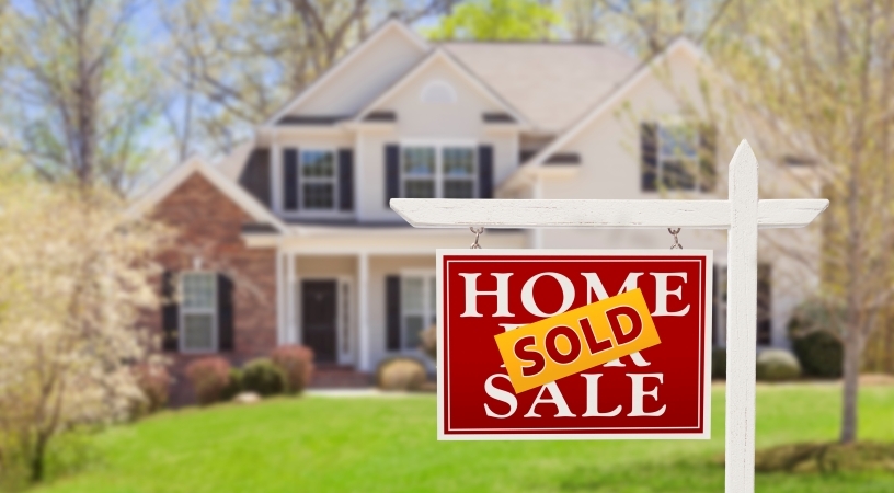 A two-story home in Charlotte, NC, with a “Home for Sale” sign in the front yard that has a large “SOLD” sticker across it.