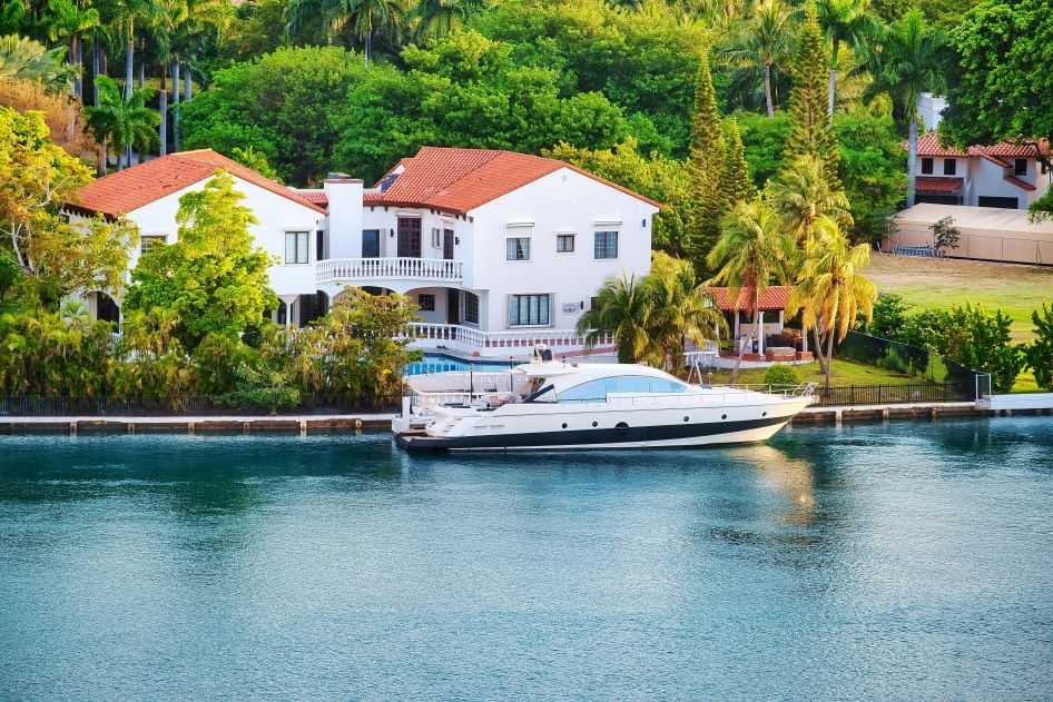 A white waterfront home with a boat in front of it in a family friendly neighborhood in Miami.