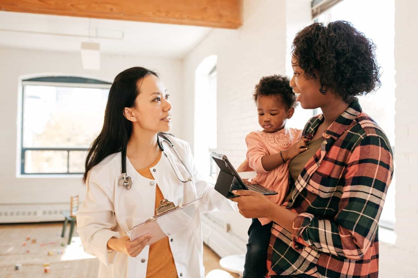 A mother with her baby in her arms consults a pediatrician in a sparsely decorated room