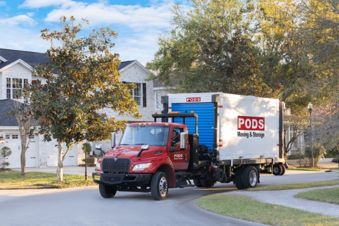 A PODS truck is delivering a portable storage container to a suburban home, providing portable storage in San Diego for flexible moving and storage needs.