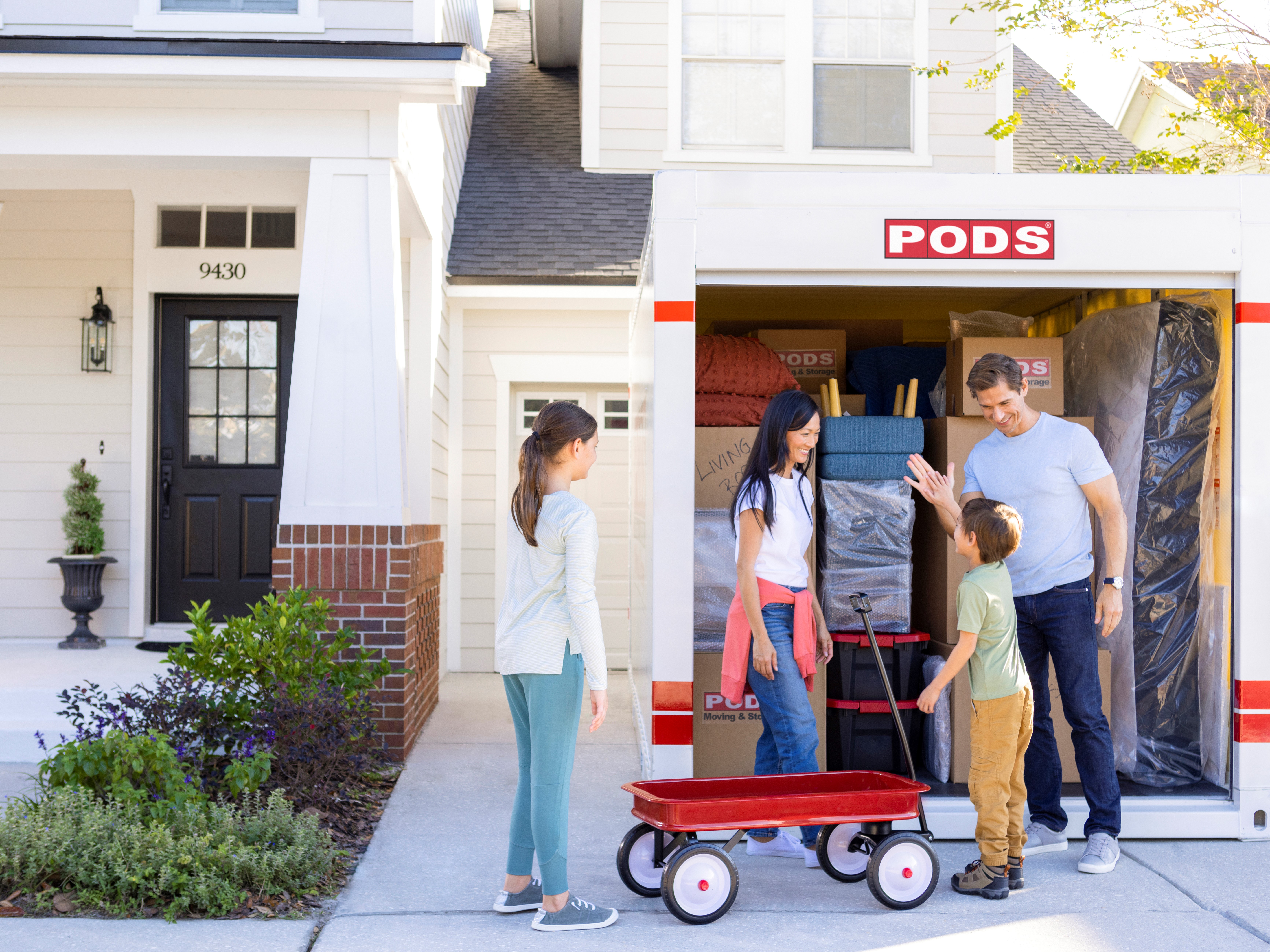 A family of four loads up their PODS container. Dad high-fives his son as they wrap up. 