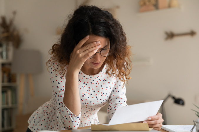 A woman holds her head, poring over the details of her house offers