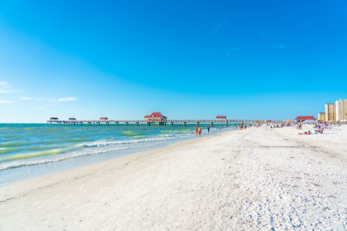 Locals enjoy a sunny day relaxing in the sand and swimming in the turquoise waters of Clearwater Beach — one of the main perks of living in Clearwater, FL.